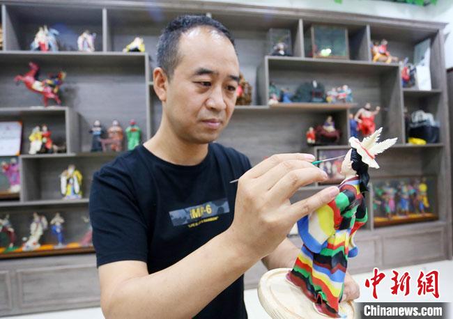 圖為安秋平正在創作代表隴南文縣民俗的《白馬人》作品。 高展 攝 圖為安秋平正在創作代表隴南文縣民俗的《白馬人》作品。 高展 攝