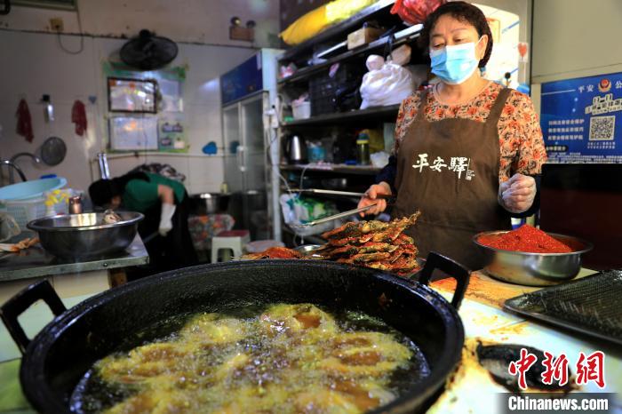圖為平安驛·河湟民俗文化體驗地內的商戶炸干板魚。 薛蒂 攝 圖為平安驛·河湟民俗文化體驗地內的商戶炸干板魚。 薛蒂 攝